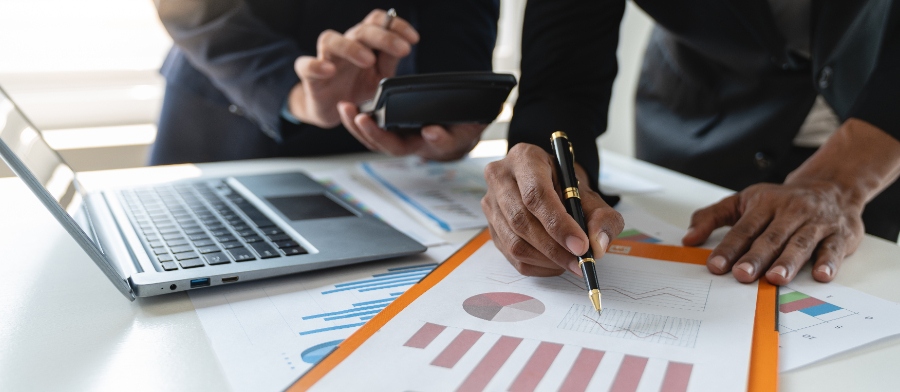 Un client et un expert-comptable en train de discuter autour d’une table avec une calculatrice posée au centre