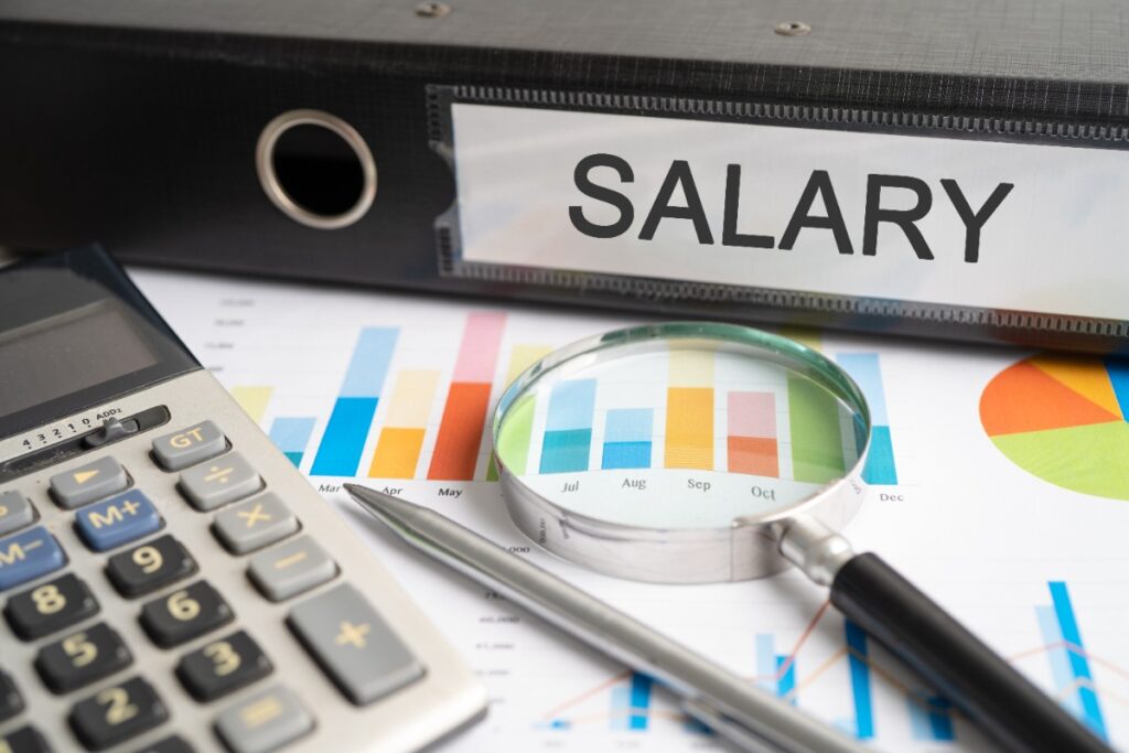Des documents contenant des fiches pour les salaires et une calculatrice sur la table