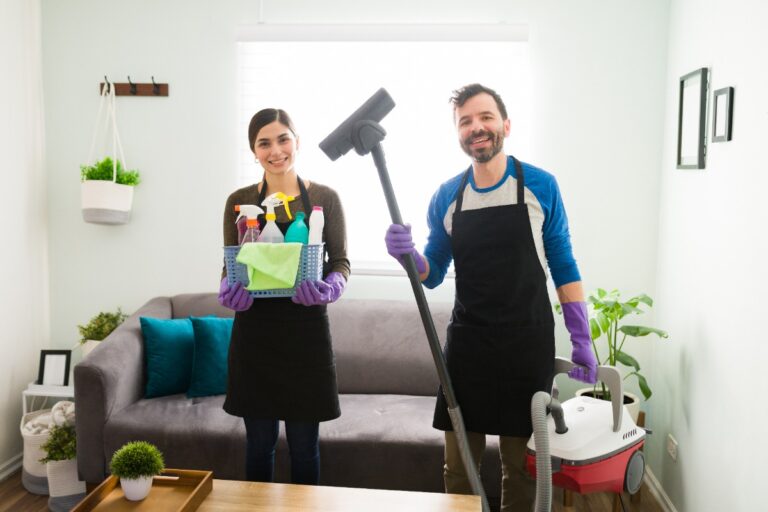 Un équipe de nettoyage souriant et tenant des matériels de nettoyage