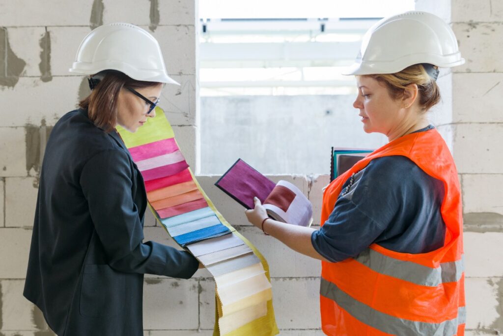 Des femmes portant des casques de chantier et choisissent des peintures