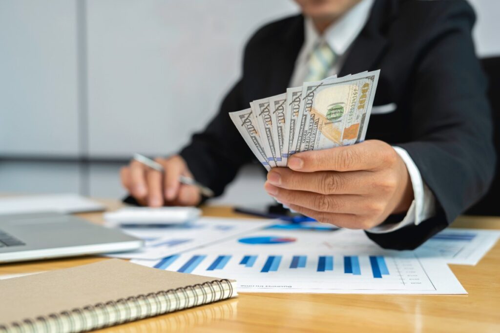 Un homme assis dans son bureau et tenant des argents
