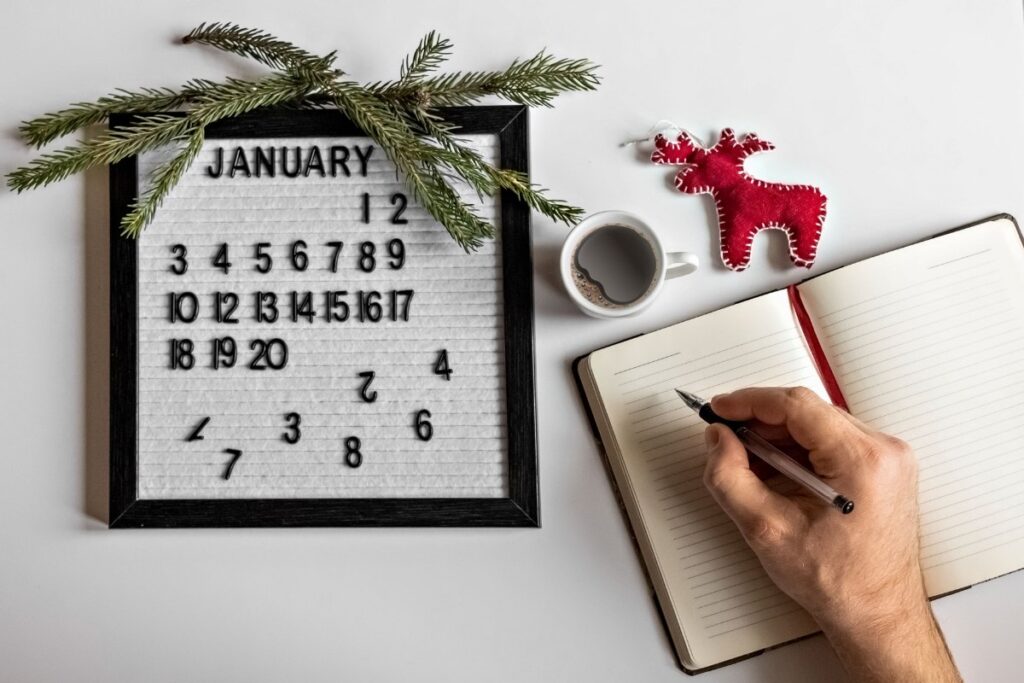 Une personne qui écrit sur un carnet sur la table avec un calendrier 