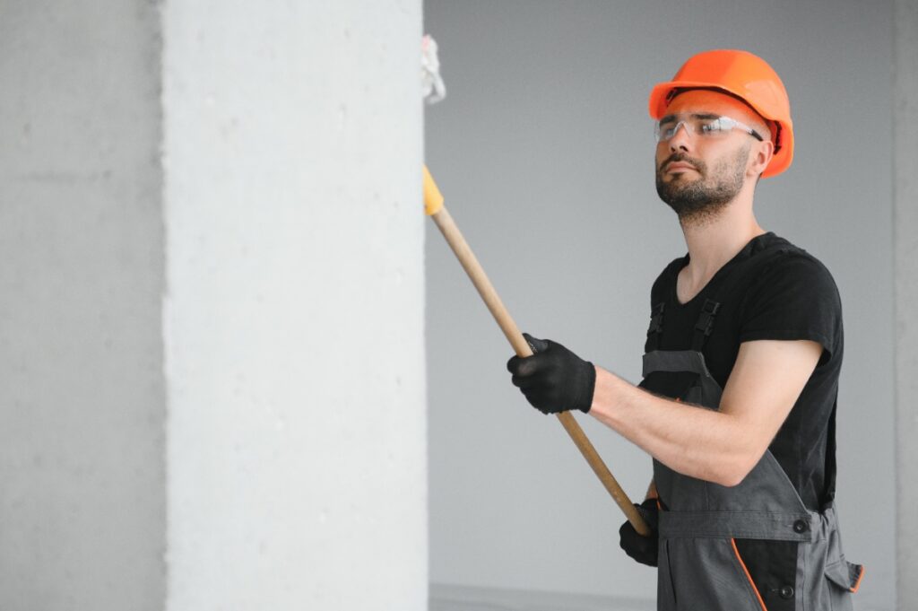 Un ouvrier qui peint le mur avec un rouleau de peinture