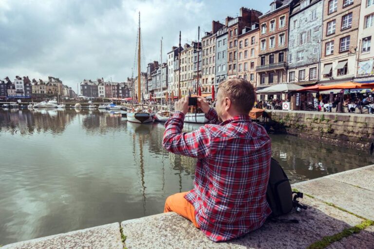 Un homme assis sur une jetée et prenant des photos