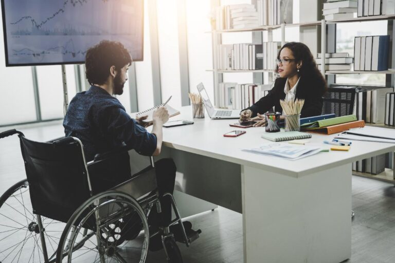 Un homme en fauteuil discutant avec une femme dans un bureau