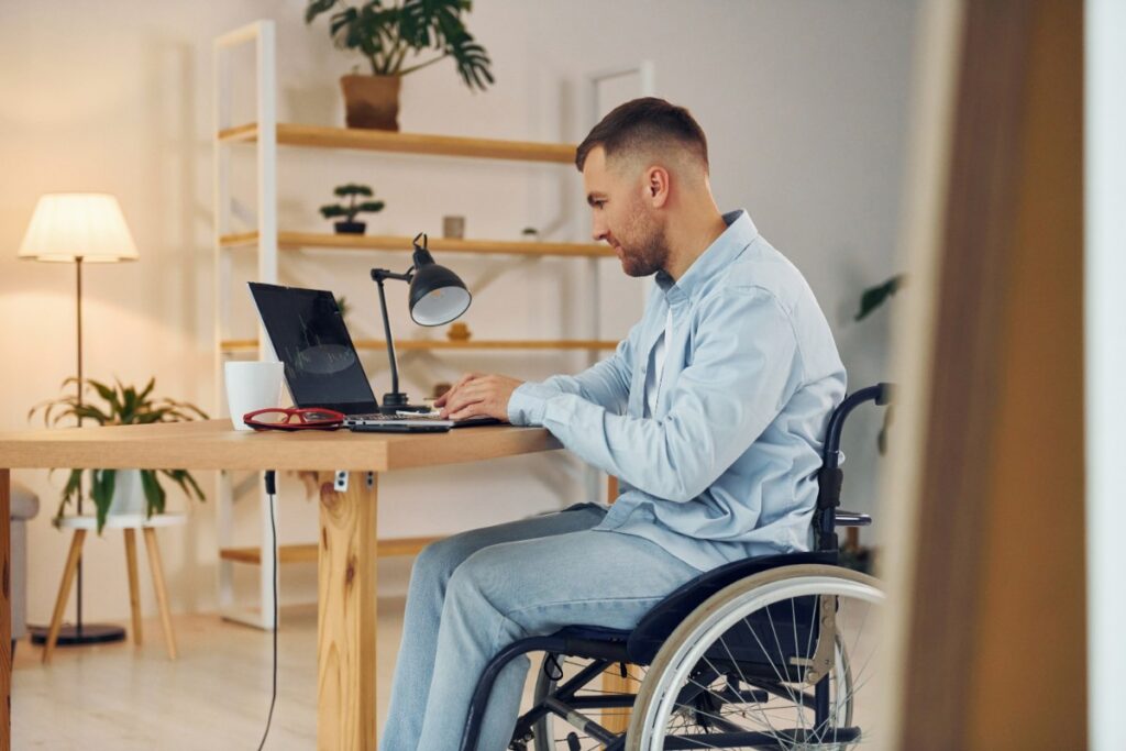 Un homme en fauteuil travaillant sur un ordinateur portable