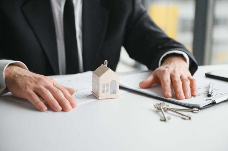 Une personne assise dans un bureau avec un contrat et une clé de maison sur la table