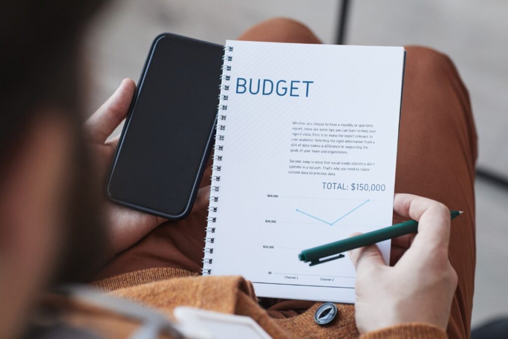 Une personne tenant son téléphone et faisant un budget de planification des affaires