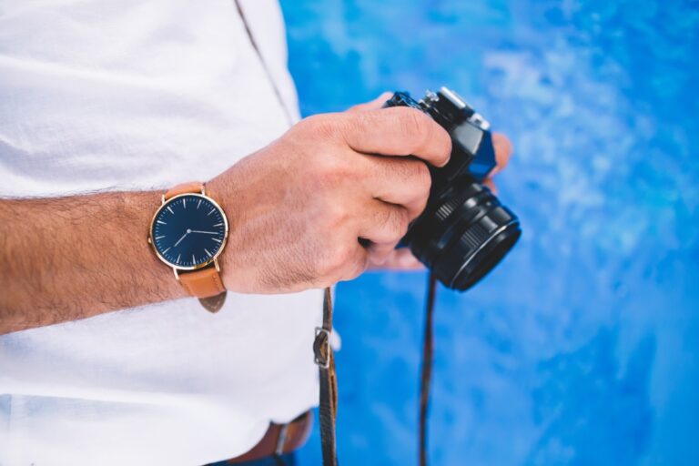 Un photographe professionnel tenant son appareil avec une montre à son poignet